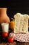 Still life on a brown and black background. In the photo, milk, hleb, jug, tomatoes and Balgarian pepper.