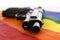 Still life with close up gun resting on gay parade flag representing sexual discrimination and intolerance