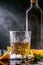 Still life with cognac glass and bottle, splashes of droplets on a black background