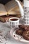 Still life composition of chocolate cookies on the plate, coffee cup, coffee pot and books. Food photo