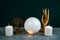 still life with a crystal ball, statuette of the God Shiva and white candles on a black background