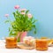 Still life with cups of tea, pieces of cake, bouquet of pink flowers in a pink pot, marshmallow on a white wooden table