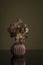 Still life with a deep red vase and blooming orchids on a olive green still life background