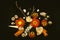 Still life of a dry branch, withered flowers of orange gerbera, dry rosebud among shells and small stones with orange feathers and