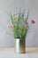 Still life fresh beautiful wildflowers and green grass in metal can on wooden table on gray background