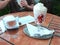 Still life - glass of mineral water, strawberries with whipped cream and paper menu on a table at a garden restaurant