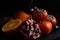 Still life of halves of pomegranate, persimmon, apples, orange and sweet cherry on a black background