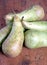 Still life with heap of long ripe green pears on wooden table front view