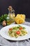 Still life - Homemade pasta from basil and arugula with green pesto in a white plate on a dark background.