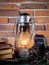 Still life kerosene lamp shines on wooden desktop stone brick background book camera.