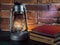 Still life kerosene lamp shines on wooden desktop stone brick background book camera.