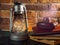 Still life kerosene lamp shines on wooden desktop stone brick background book camera.