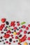 Still life of multi-colored berries on gray background. Red currants, raspberries red and yellow, blueberries, green mint