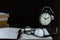 Still life with old clock on desk with books, alarm clock and glasses