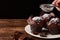 Still life on old wooden board table with three cocoa muffins with sugar and pieces of chocolate. Female hand holding strainer on