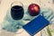 Still-life. red Apple, blue notebook, glass of wine and turquoise fabric on light background