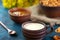 Still life in a rustic style. Crumbled pretzels on a textural background with milk in a clay cup, with apricot jam in a clay plate