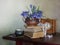 Still life with spring flowers snowdrops, old books clock on the table.