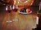 Still life with two glasses of red wine in focus, Bottle and cork in foreground out of focus, Plate with grapes and apple out of