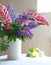 Still-life, white vase with purple and pink lupine on the table, selective focus on Lupines