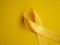 Still life a yellow cancer awareness ribbon on a yellow background. 15 February Childhood Cancer Awareness day concept