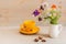 A still life, a yellow mug on a saucer, flowers in a white jug, and a star anise  on the table. Morning tea