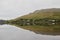 Still water creates a reflection of homes along a lake in rural Connemara in western Ireland