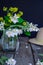 Stilllife card with jasmine flowers in glass jar, separate branches with flowers, petals and straw hat on the wooden rustic table.