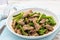 Stir fried pork with onion scape and buds on the white plate