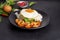 Stir-fried shrimp with basil Thai street food arranged on a black plate with a fried egg Thai spicy food Placed on a dark black