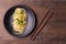 Stir-fried spaghetti or stir-fried noodles Tomato sauce and prawns on a black plate On a wooden table background. Top view