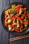 Stir-fried teriyaki beef with red and yellow bell pepper, broccoli and sesame seeds close-up on the table. Vertical top view