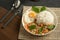 Stir-fried Thai basil with minced pork meat, carrots, and baby corns, with fried egg and fresh basils sort in a white dish on