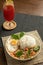 Stir-fried Thai basil with minced pork meat, carrots, and baby corns, with fried egg and fresh basils sort in a white dish on