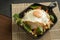 Stir-fried Thai basil with minced pork meat, carrots, and baby corns, with fried egg and fresh Thai basils sort in a black small