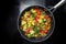 Stir-fried vegetable meal from broccoli, bell pepper, onion and tomato in a frying pan on the black stovetop, vegetarian cooking