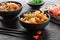 Stir fry noodles or wok noodles with shrimps and vegetables in a black bowl, sushi roll set and seaweed salad