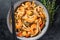 Stir-fry udon seafood noodles with shrimp prawns in a bowl. Black background. Top view