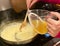 Stirring in broth to a risotto rice in a frying pan on a home stove