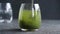 Stirring green barley grass powder in a glass of water - preparation of a healthy drink