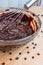 Stirring melted chocolate chips in bowl with whisk up-close on wood table