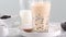 Stirring tapioca pearl bubble milk tea in drinking glass, tasty Taiwanese popular drink on bright marble table. Homemade concept.