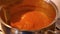 Stirring thick tomato sauce with a wooden cooking spoon