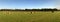 Stitched Panorama of Hay Bales on Green Field