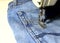 Stitching, stitching a hole in jeans with a sewing machine. Part of sewing machine and jeans cloth closeup. Tailoring