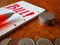 Stock of coins, notepad with the word Bill! before the pen tip and a pile of coins in the foreground