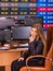 Stock exchange people. Trader woman sitting table surrounded by monitors.