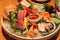 Stock image of a colorful platter of sashimi sushi with tuna and crab sticks in foreground and cucumber decorations