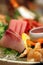 Stock image of a colorful platter of sashimi sushi with tuna and crab sticks in foreground and cucumber decorations