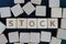 Stock market, equity investment asset concept, straggle cube wooden blocks with some combine the word Stock with white retro alarm